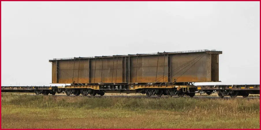 Flatcar railcar carrying a large metal structure, illustrating its weight capacity and suitability for heavy equipment transport