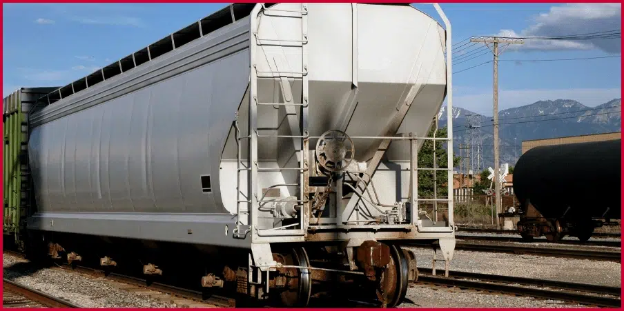 Hopper railcar with a sloped design on tracks, ideal for transporting bulk materials like grain or coal in industrial settings