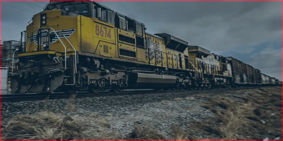 Yellow freight train with railcars traveling on tracks under cloudy skies, highlighting railcar weight and transportation capacity