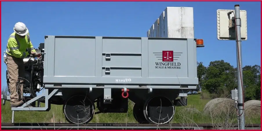 Wingfield Scale's fully autonomous solar-powered railroad scale installation, featuring a technician working on a custom railcar weighing system for precise measurements in remote locations